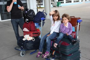 Zwei Mädchen und viele Koffer auf dem Rollwagen am Flughafen