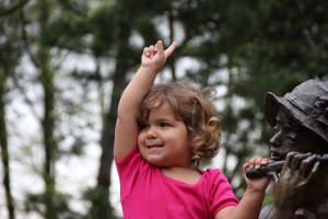 Kleines Mädchen mit Statue und erhobenem Zeigefinger